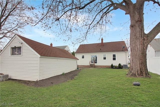 rear view of property with central AC, entry steps, fence, and a yard