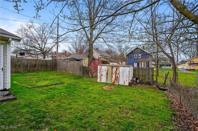 view of yard featuring a fenced backyard, an outdoor structure, a residential view, and a storage shed