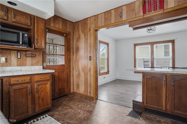 2510 E Midlothian Blvd, Youngstown, OH 44502 - kitchen featuring light countertops, baseboards, wooden walls, and brown cabinetry