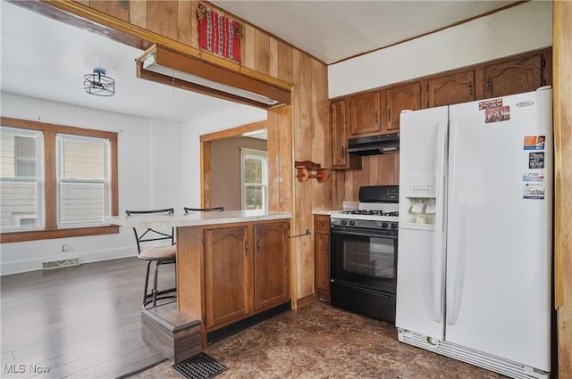 2510 E Midlothian Blvd, Youngstown, OH 44502 - kitchen featuring white fridge with ice dispenser, gas range oven, under cabinet range hood, light countertops, and brown cabinetry