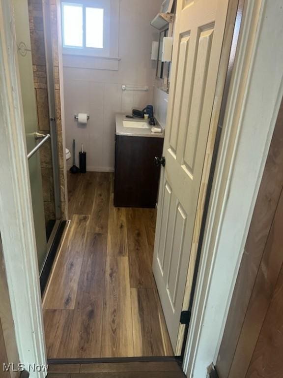 full bath featuring toilet, a stall shower, hardwood / wood-style flooring, vanity, and baseboards
