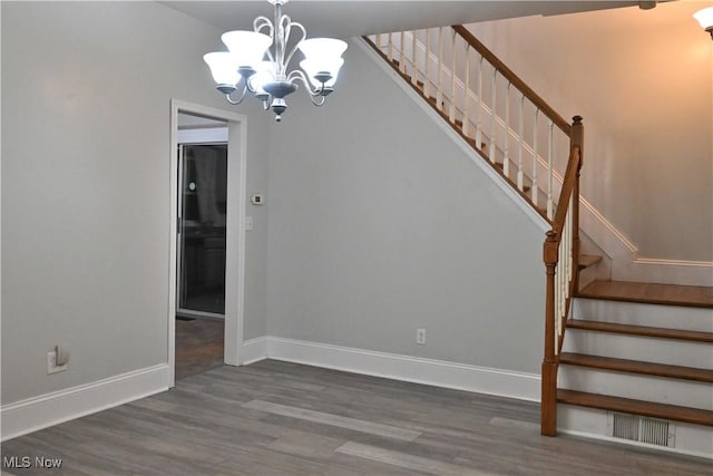 stairway featuring visible vents, baseboards, a notable chandelier, and wood finished floors