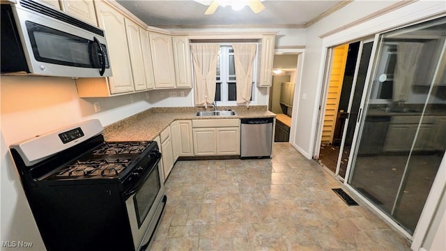 kitchen featuring crown molding, visible vents, appliances with stainless steel finishes, a sink, and stone tile flooring