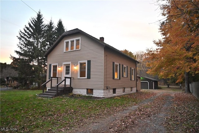 bungalow-style house featuring an outdoor structure, a lawn, and a chimney
