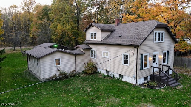 back of property featuring a chimney, a shingled roof, fence, and a yard
