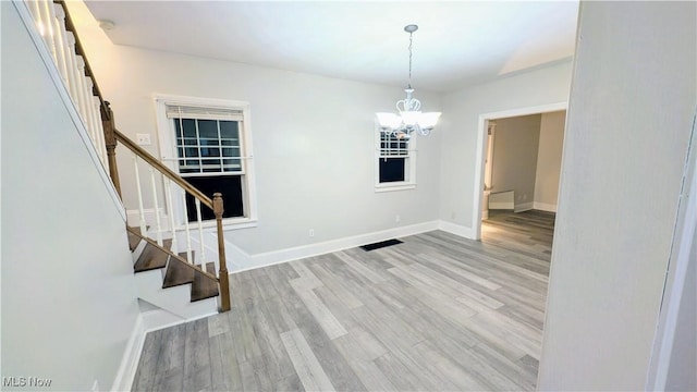 unfurnished room with baseboards, stairway, a chandelier, and wood finished floors