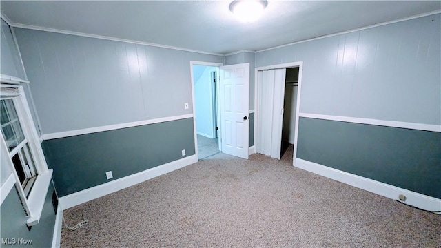 unfurnished bedroom featuring crown molding, a closet, baseboards, and carpet floors
