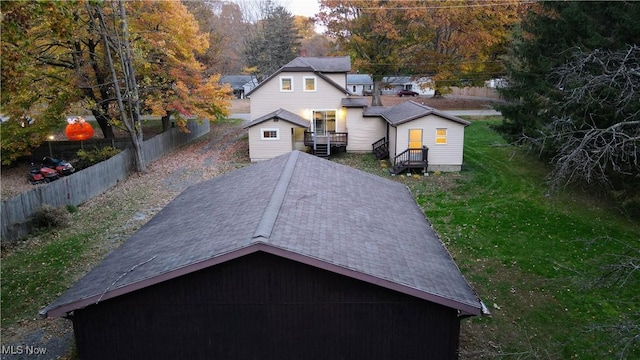 view of front of home with a front yard, an outdoor structure, a wooden deck, and fence