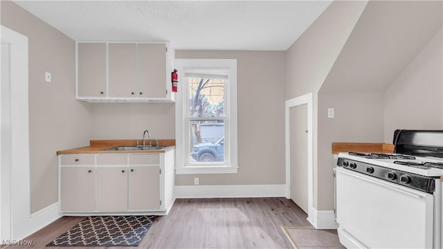 804 E Ave, Elyria, OH 44035 - kitchen featuring a sink, light wood-style flooring, white gas range, and baseboards