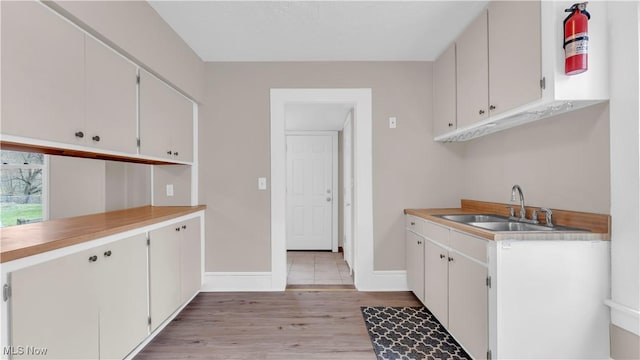 804 E Ave, Elyria, OH 44035 - kitchen with light wood-style floors, white cabinets, a sink, light countertops, and baseboards