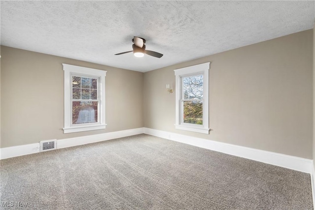 carpeted spare room with visible vents, baseboards, a ceiling fan, and a textured ceiling