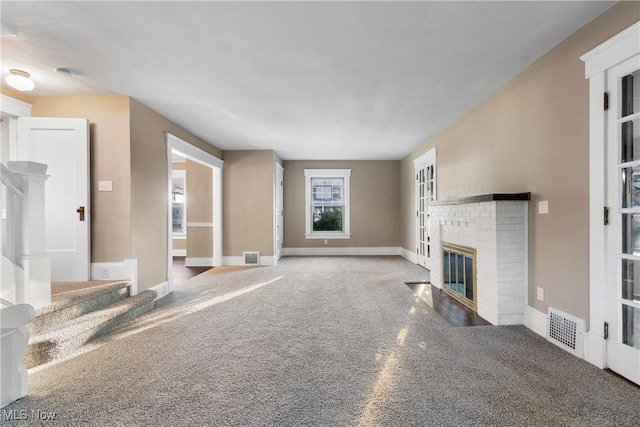 unfurnished living room with baseboards, a fireplace, visible vents, and carpet floors