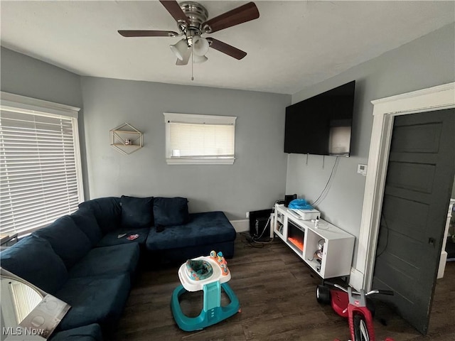 living room featuring ceiling fan, baseboards, and dark wood-style flooring
