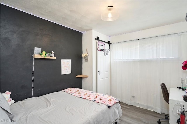 bedroom with a barn door and wood finished floors