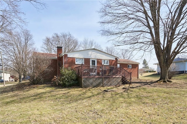 rear view of house featuring a chimney, a yard, a deck, and brick siding