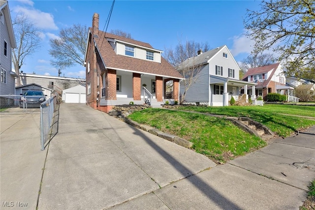 bungalow-style house featuring a porch, a front yard, an outdoor structure, and brick siding