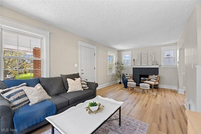 living area featuring a textured ceiling, baseboards, and light wood-type flooring