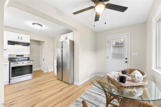 kitchen with light wood-style flooring, white cabinetry, under cabinet range hood, stainless steel appliances, and baseboards