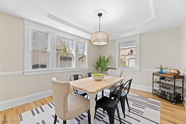 dining area with plenty of natural light, light wood finished floors, a tray ceiling, and baseboards