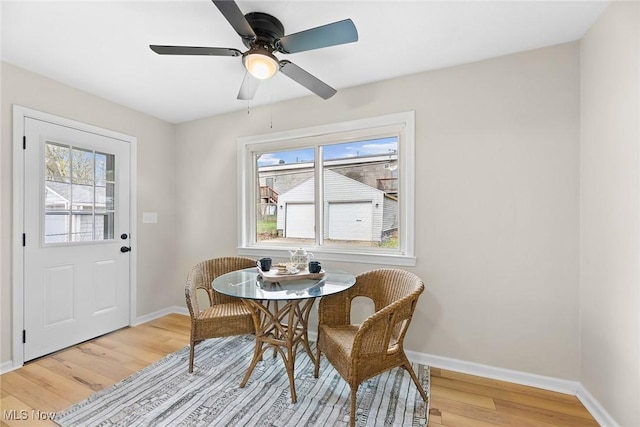 dining room featuring light wood-style floors, baseboards, and a ceiling fan