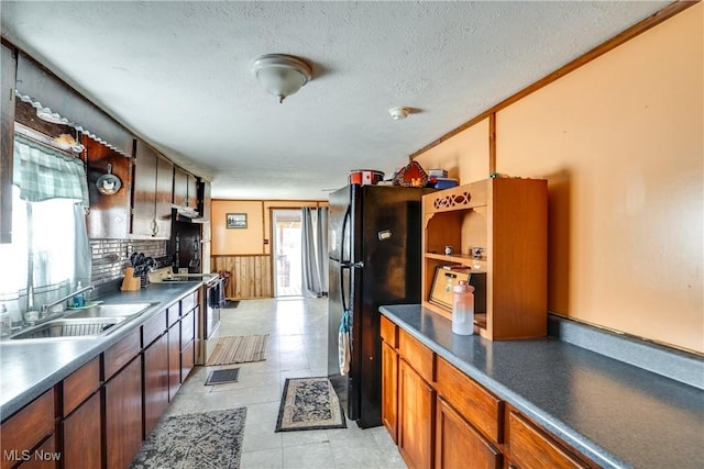 kitchen with freestanding refrigerator, a textured ceiling, a sink, and electric range oven