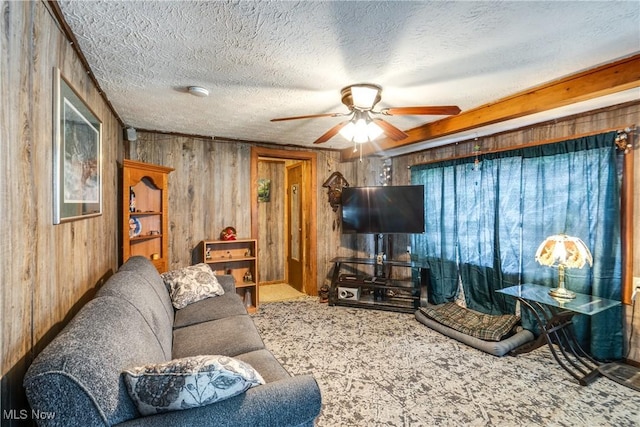 living area featuring wood walls, a ceiling fan, carpet flooring, and a textured ceiling