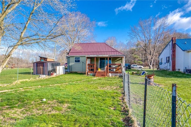 exterior space with a front lawn, an outdoor structure, covered porch, and metal roof
