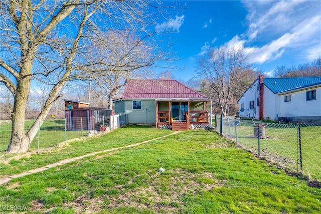 rear view of house featuring an outdoor structure, a porch, a yard, metal roof, and fence