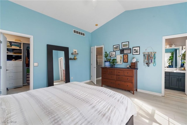bedroom featuring visible vents, a closet, a walk in closet, ensuite bath, and high vaulted ceiling