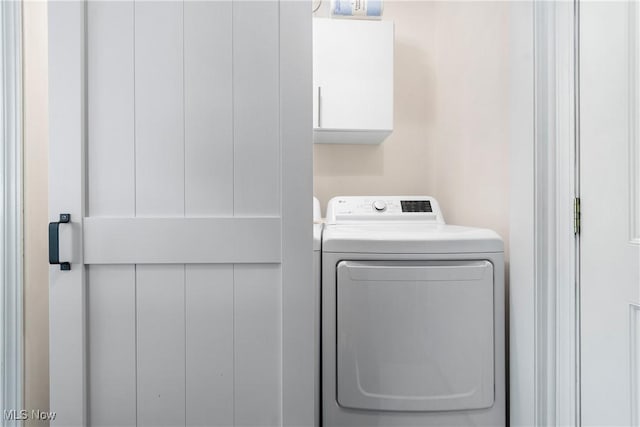 clothes washing area featuring washing machine and dryer and cabinet space