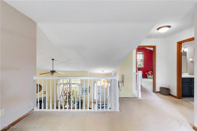 hallway with carpet, baseboards, and an upstairs landing