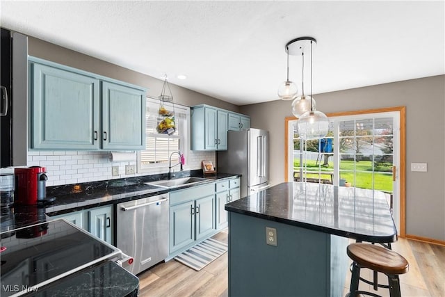 kitchen featuring backsplash, light wood-style floors, a kitchen bar, appliances with stainless steel finishes, and a sink