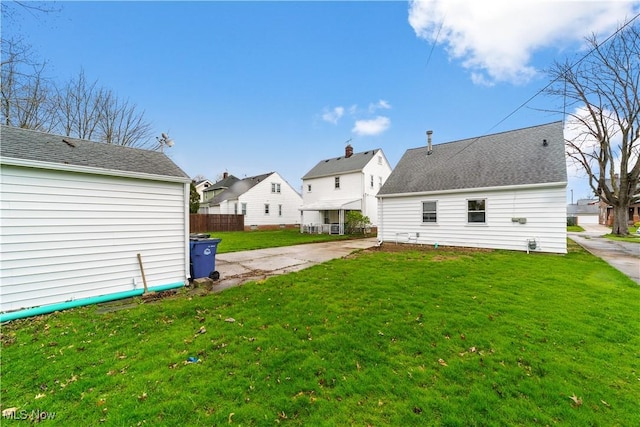 rear view of house with fence, a residential view, and a lawn