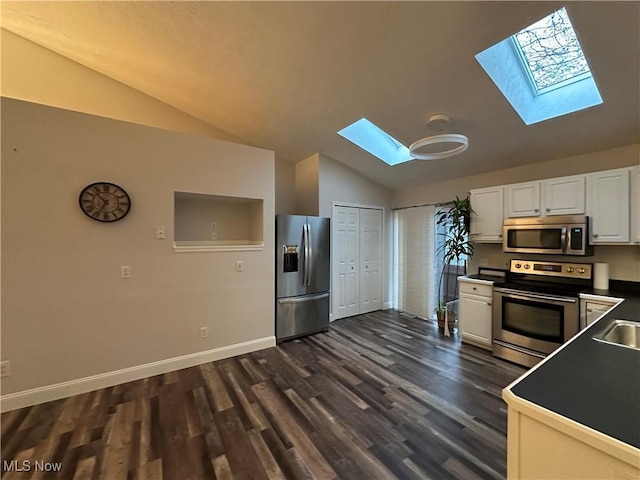 kitchen featuring vaulted ceiling with skylight, dark wood-style floors, white cabinets, and stainless steel appliances