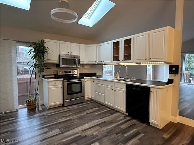 kitchen with white cabinets, a sink, appliances with stainless steel finishes, dark wood-style floors, and lofted ceiling with skylight