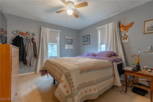 bedroom with light carpet, a textured ceiling, baseboards, and ceiling fan