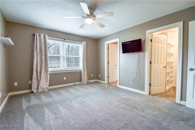 unfurnished bedroom featuring carpet floors, ensuite bath, baseboards, and ceiling fan