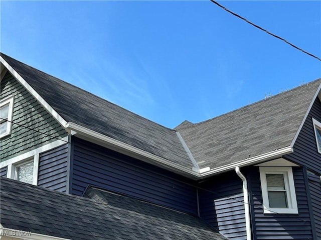 details with roof with shingles, a downspout, and gutters
