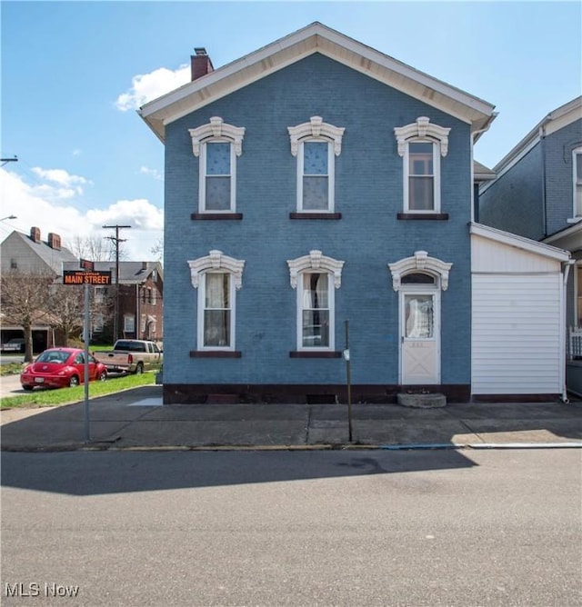 italianate-style house featuring a chimney