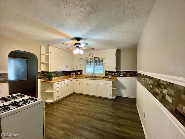 kitchen featuring white gas range oven, a textured ceiling, a ceiling fan, open shelves, and a sink