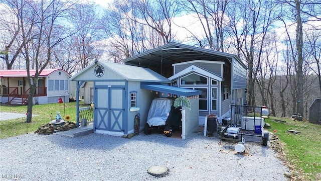 view of shed with a detached carport and gravel driveway