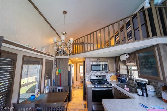 kitchen with a notable chandelier, a high ceiling, a sink, light countertops, and appliances with stainless steel finishes