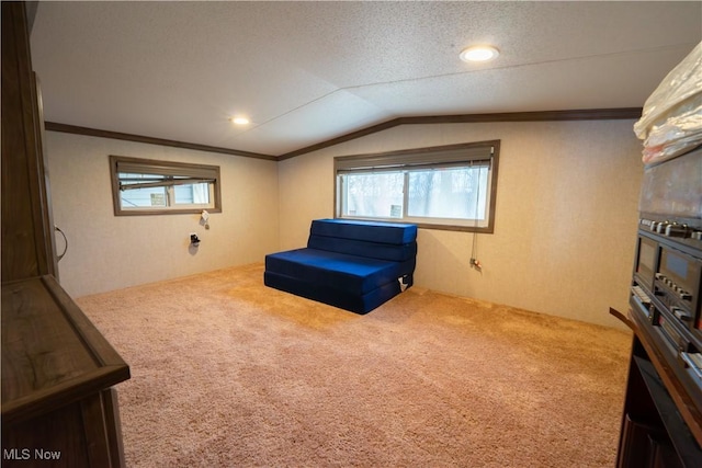 sitting room featuring vaulted ceiling, carpet floors, ornamental molding, and a healthy amount of sunlight