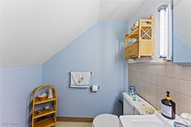 half bathroom with vaulted ceiling, toilet, and a sink
