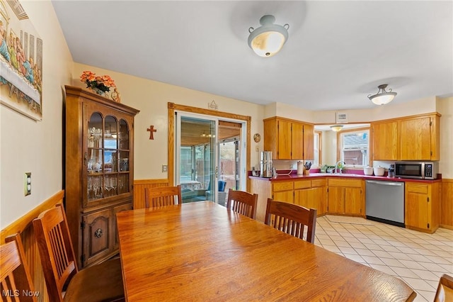 dining room with wainscoting, light tile patterned floors, and a healthy amount of sunlight