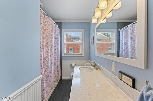 full bathroom featuring wainscoting, toilet, ornamental molding, and vanity