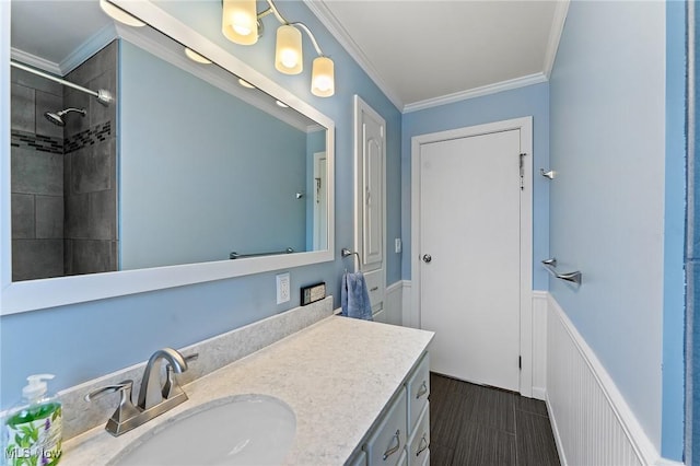 full bathroom with wainscoting, a decorative wall, ornamental molding, and vanity