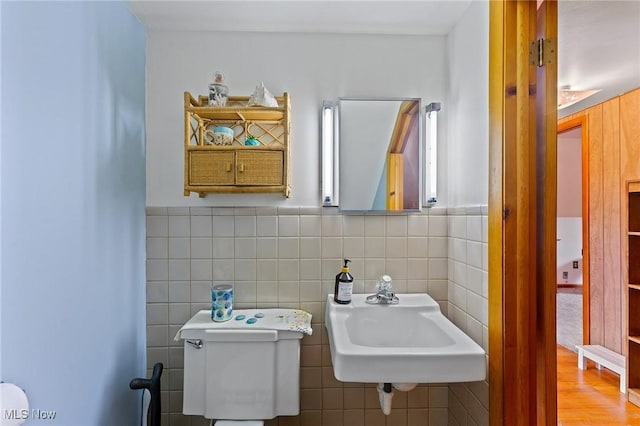 bathroom with tile walls, wainscoting, a sink, and toilet