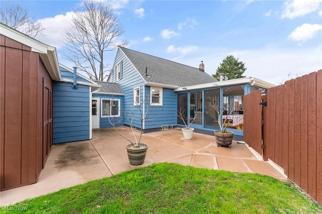 rear view of property with a patio area, fence, a yard, roof with shingles, and a sunroom