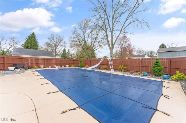 view of pool with a fenced backyard, a water slide, a patio area, and a fenced in pool